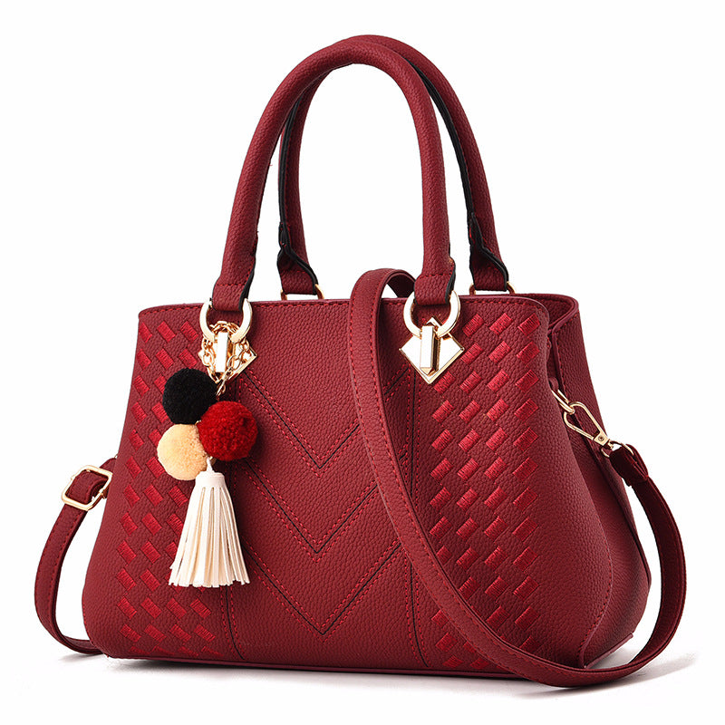 Embossed top handle handbag with pompom